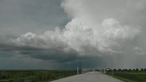 4K - Stormy rural road with thunderstorm on the horizon. Heavy rain shaft with deep cloud structure.