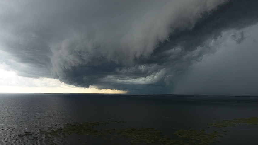Aerial severe thunderstorm with large shelf cloud and rain core over Lake Okeechobee and Florida Everglades. Descending moving shot.