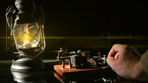 The flame from an oil latern throws a lens flare across a telegrapher sending a telegraph message.