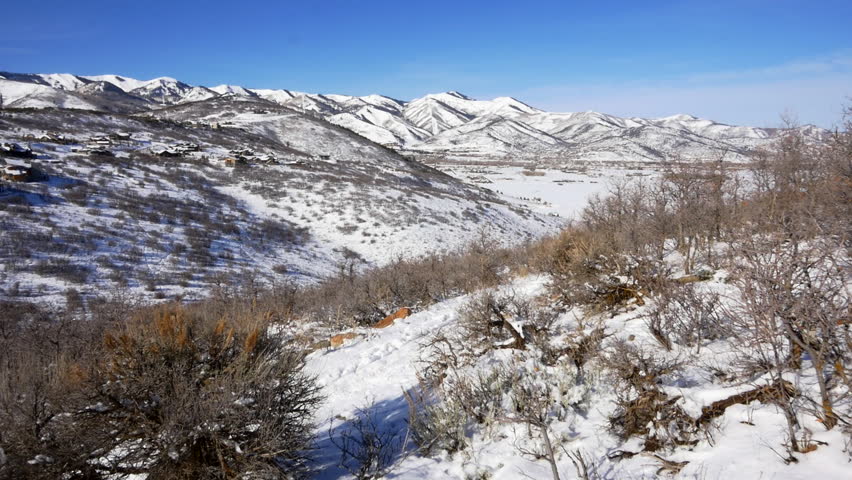 Medium shot of female and male couple winter fat-tire mountain biking on single-track trail with view in Park City, Utah.
