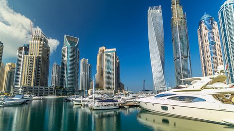DUBAI - CIRCA JANUARY 2016: Beautiful view from Promenade on Dubai Marina tallest modern Towers and floating yachts and boats timelapse hyperlapse at night, United Arab Emirates. Dubai Marina is a
