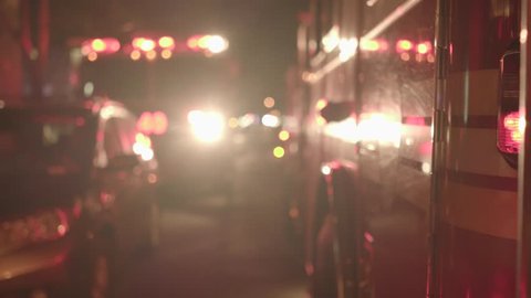 fire department trucks with flashing siren lights standing in the city streets at night. rescue emergency scenery background