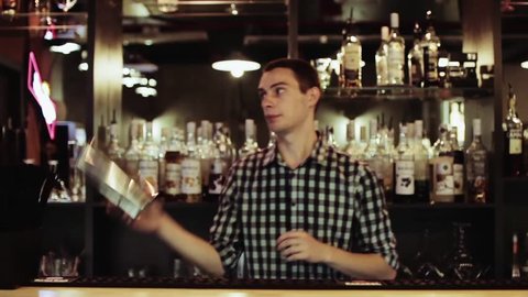Bartender making amazing tricks with two glasses, standing behind the bar