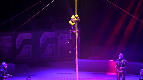 ST. PETERSBURG, RUSSIA - JANUARY 2, 2016: Brothers Zapashny circus, "UFO. Alien Planet Circus" show in Saint Petersburg. Gymnast climbs the pole using hands only. Others stand around