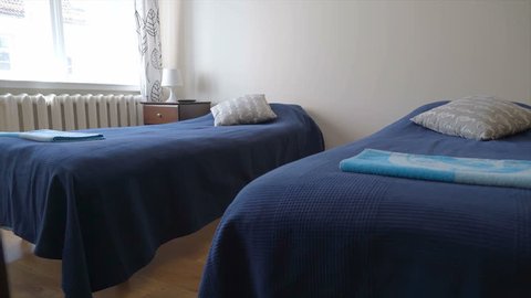 Two clean beds inside the hostel room they have both blue cover on top of it