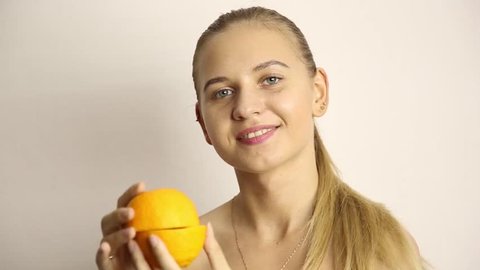 beautiful naked young woman eating an orange. healthy food - strong teeth concept
