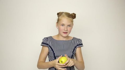 beautiful young girl dressed in a striped dress eating an apple. healthy food - strong teeth concept