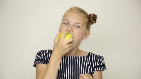 beautiful young girl dressed in a striped dress eating an apple. healthy food - strong teeth concept