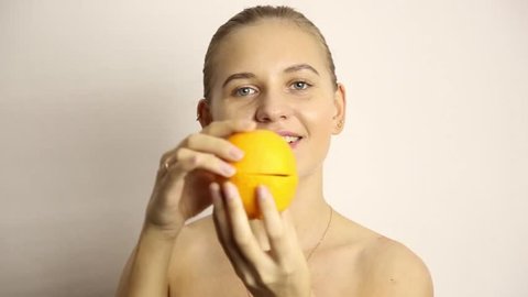 beautiful naked young woman eating an orange. healthy food - strong teeth concept