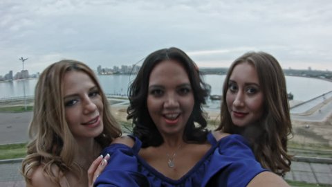 Three Attractive young women on high hill get a selfie, pov
