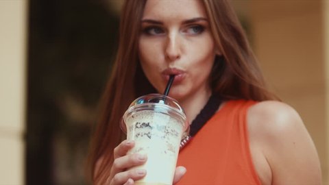 EXTREME CU Urban portrait of young attractive Caucasian female drinking milkshake. 60 FPS 4K UHD