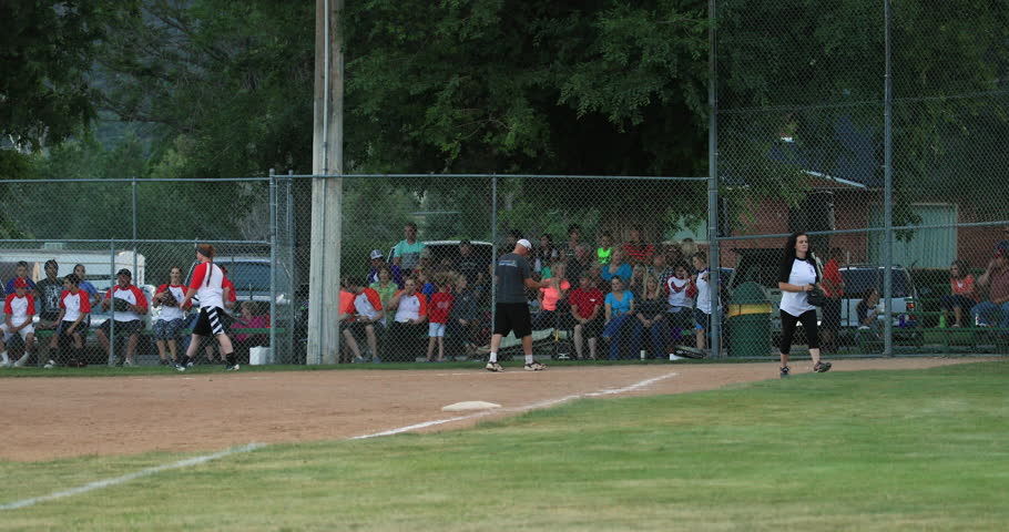 FOUNTAIN GREEN, UTAH - JUL 2016: Softball rural community end of inning. Volunteers umpire. Team spirit and teamwork with youth, teenagers and parents. Sports, recreation and healthy exercise.