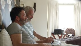 Gay Couple Researching On Laptop In Hotel Room Shot On R3D - Powered by Shutterstock - Get 15% off with code: PIKWIZARD15