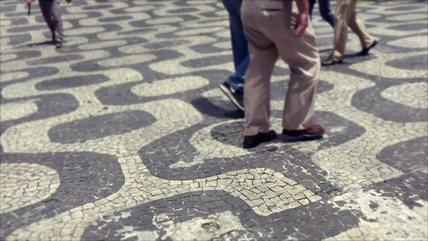 Pedestrians walk on the iconic sidewalk tile pattern in the downtown business district of Centro in Rio de Janeiro, Brazil 