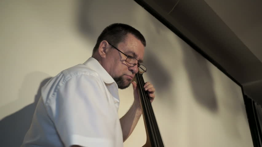 Contabass man and jazzband in restaurant.