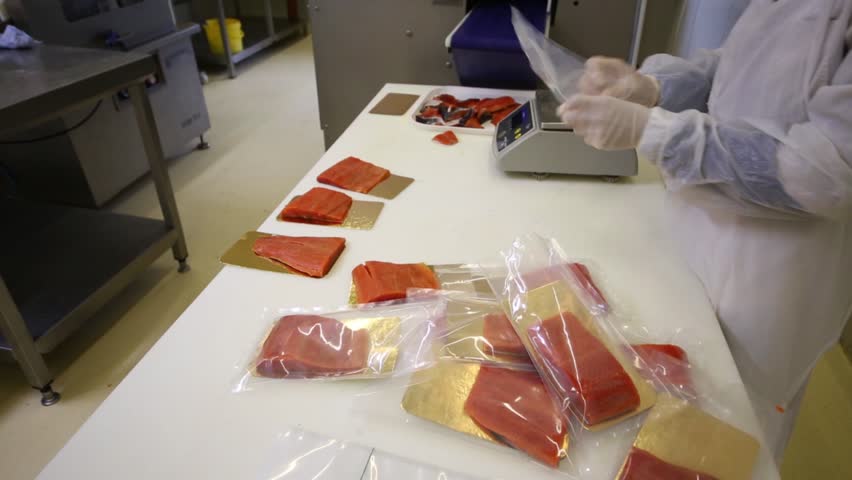 Employee puts salt fish on the foil paper in the package in the factory