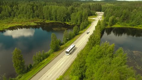 Aerial Shot of Bus Riding on Highway Surrounded by Large Forest