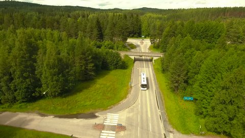 Aerial Shot of Bus Riding on Highway Surrounded by Large Forest