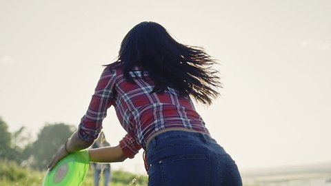 Slow Motion Shot Of A Young Girls Throwing A green disc at summer day on meadow