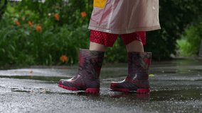 Kid in rain boots jumping chaotically in puddle