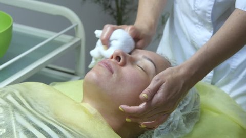Hands of beautician are preparing the skin for the procedure or cleaning after the procedure. Beautician hands stroking the face of the client. Cosmetologist doing massage of female face. Close-up.