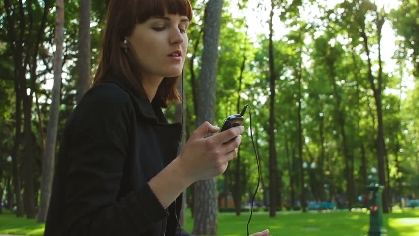 Girl Sitting and Listing to Music in the Park