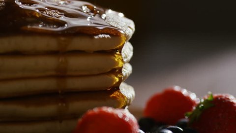 4K Camera follows maple syrup being poured over hot stacked pancakes and fruit