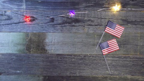 Flashing red, white and blue lights and American flags on wooden surface with copy space.