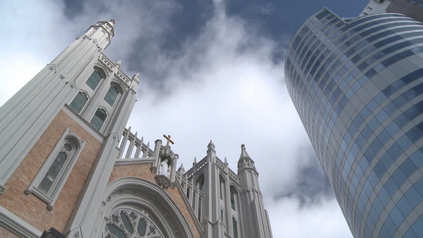 Time lapse of clouds above a church and modern office tower
