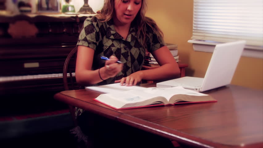 a A woman works on a laptop in her home.