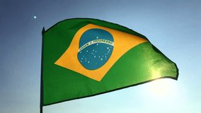 Brazilian flag flying in slow motion backlit by bright sun in Rio de Janeiro, Brazil
