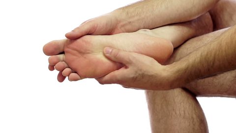 Closeup of an anonymous man isolated on a white background and rubbing his sore and painful foot and toes.