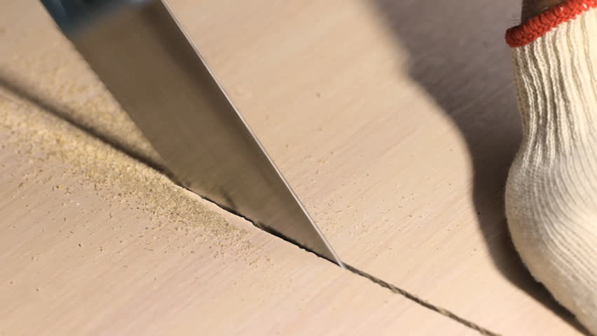 Man sawing wooden board with hand saw