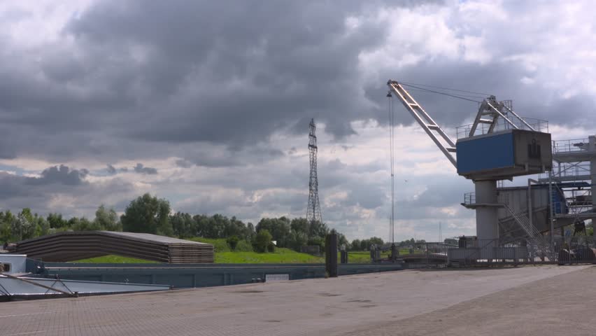 Crane bucket unloads raw material from an inland ship. Wageningen has an important inland port on the river Rhine. WAGENINGEN, THE NETHERLANDS - JULY 2016