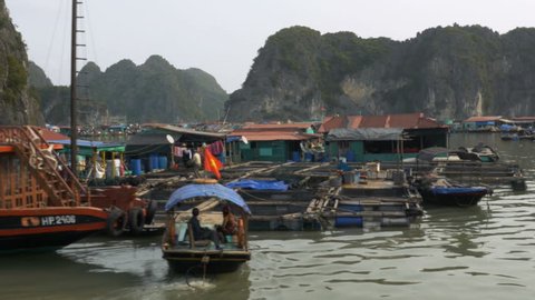 Slowly passing by a floating fishing village nearby Ha Long Bay, Vietnam. Tracking shot