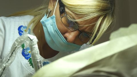 KHARKIV, UKRAINE - JULY 8, 2016: Close up portrait of female doctor in glasses with protective work wear. Female face in medical mask. Cosmetologist or therapist is working