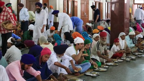 AMRITSAR, INDIA - SEPTEMBER 26, 2014: Unidentified poor indian people eating free food at a soup kitchen in the Golden Temple