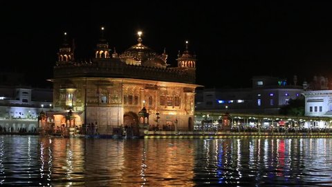 AMRITSAR, INDIA - SEPTEMBER 28, 2014: Unidentified sikhs and indian people visiting the Golden Temple in Amritsar at night. Sikh pilgrims travel from all over India to pray at this holy site