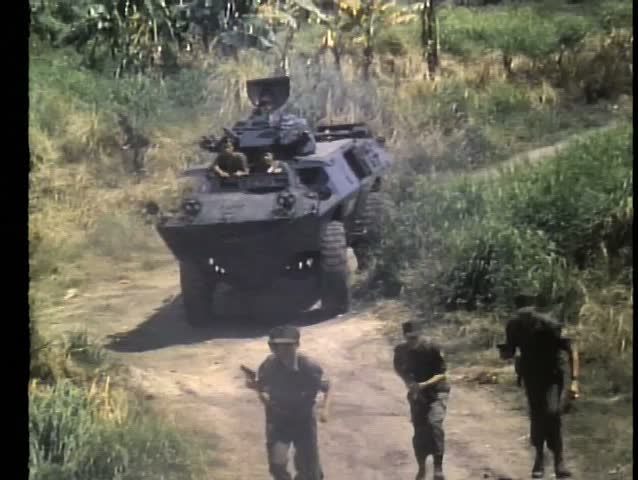 Military tanks and foot soldiers advancing down dirt road