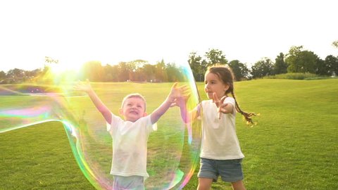 Huge soap bubbles playing bursting. Summer games with fresh air countryside. exciting Physics education Kids. dog brings a stick. Slow motion video footage. Contre-jour Backlight.  Flares flecks sun
