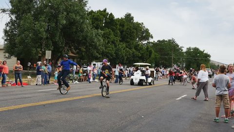 FOUNTAIN GREEN, UTAH - JULY 2016: A typical rural small town summer celebration features tractors and farm machinery on parade throwing candy to the excited children lining the parade route-Time lapse