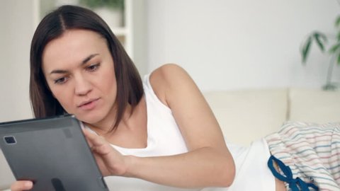 Happy woman with digital tablet lying in bed