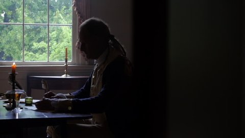 VIRGINIA - OCTOBER 2014 - Reenactment, President, founding father, Revolutionary War anniversary recreation -- Tabletop, quill writing, dipping ink and writing by candle light & by window, standing