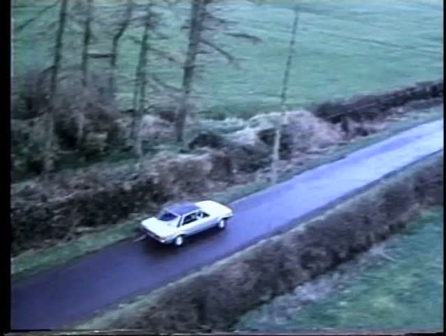 Aerial view of white car driving down rural road