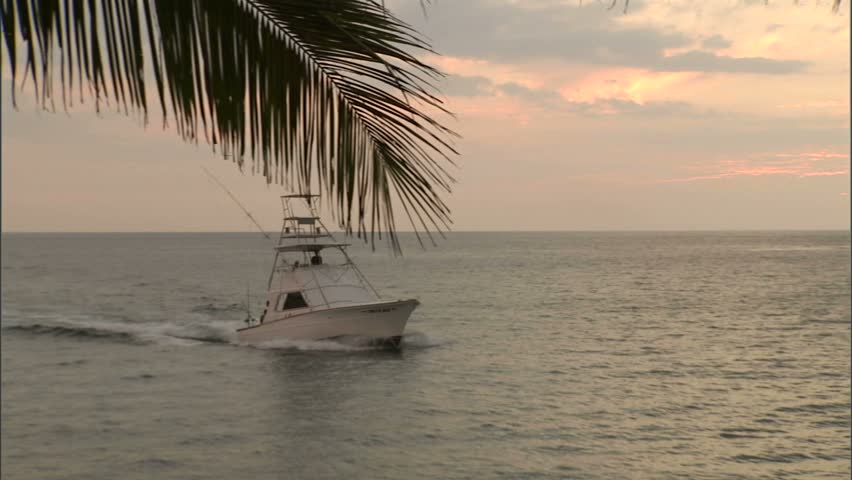 Sport fishing boat entering harbor at sunset