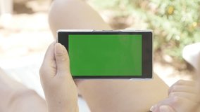 Deck chair outdoor woman relaxing with green screen tablet 4K 2160p 30fps UHD footage - Young female holding greenscreen chroma key phone on beach 4K 3840X2160 UltraHD video