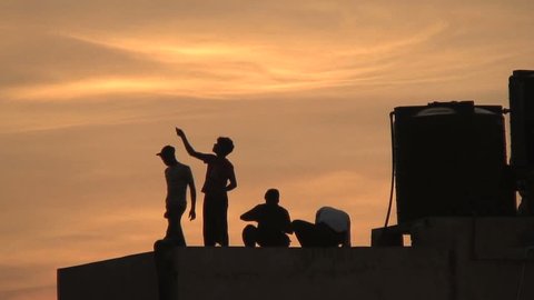 NEW DELHI, INDIA- AUGUST 7, 2006: Kids fly kites at dusk from a rooftop in New Delhi, India