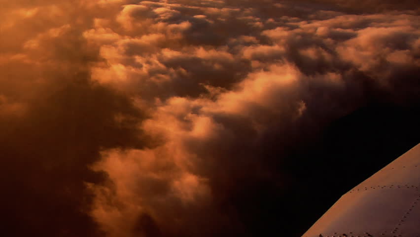 A beautiful shot from an airplane of clouds hovered on the side of a mountain