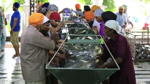 AMRITSAR, INDIA - SEPTEMBER 27, 2014: Unidentified poor indian people wash dishes at a soup kitchen in the Sikh Golden Temple