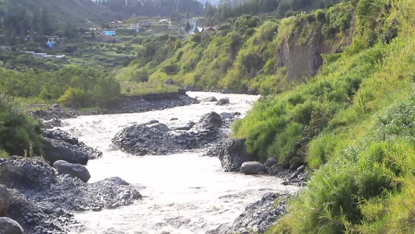 Panning over Pastaza river in Ecuador passing by the city of Banos de Agua Santa